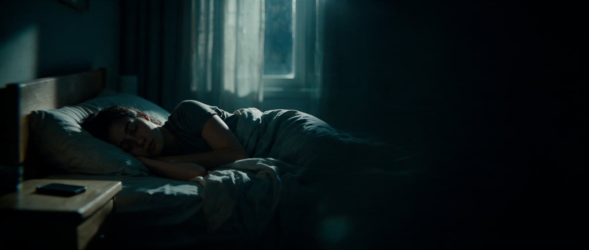 A person asleep at night, phone face down on the nightstand